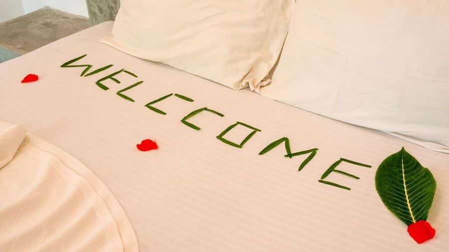 Welcome message made of leaves and petals on the bed